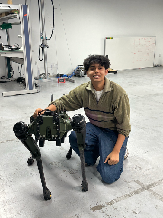 Abhay kneeling beside a robot dog